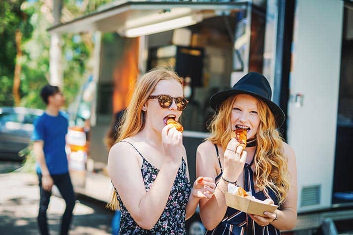 Girls enjoying empanadas from a food truck