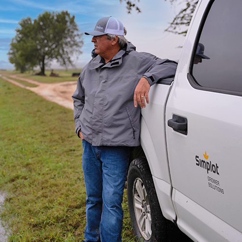Image of J.R. Simplot Company certified Crop Advisor standing beside his work truck in a farm field.