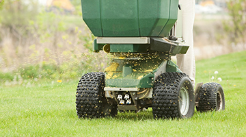 Person riding a fertilizer spreader-sprayer