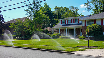 Irrigation system watering the green grass of a front lawn