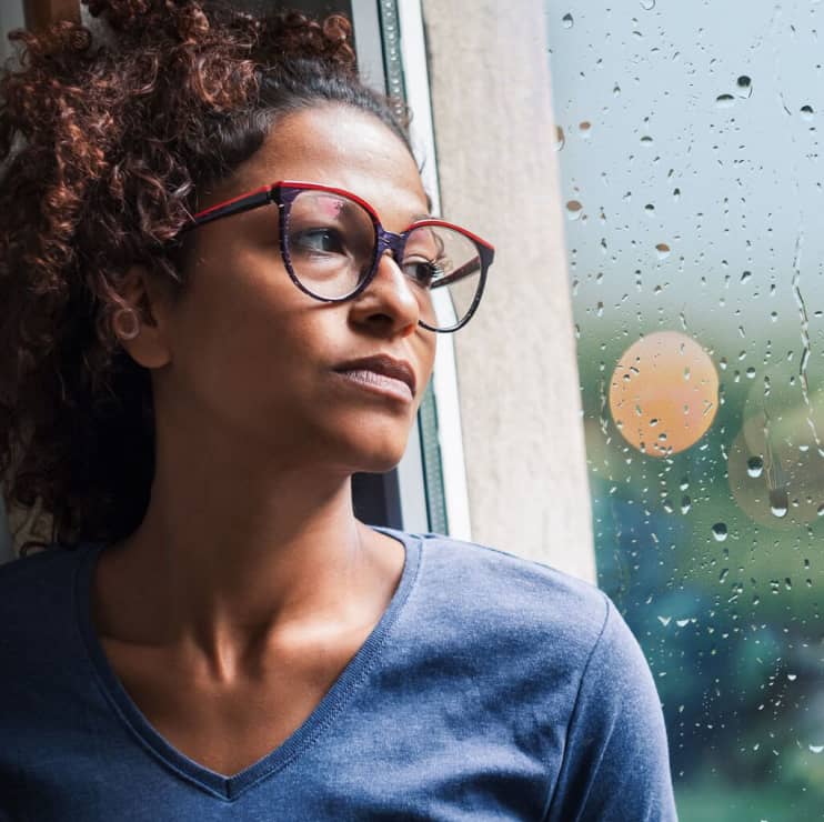 Woman looking out a window with a far-away look