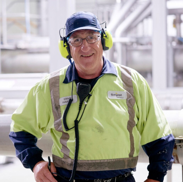 Man standing in manufacturing plant with protective sound headphones on
